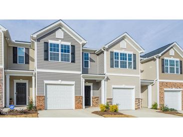 Charming townhome featuring a one car garage, neutral siding, brick accents, and a well manicured front yard at 267 Canopy Dr, Graham, NC 27253