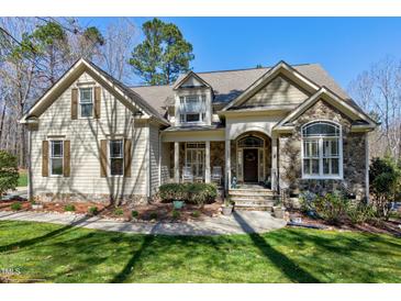 Charming home featuring a stone facade, rocking-chair front porch, and well-manicured lawn at 3655 Pleasants Ridge Dr, Wake Forest, NC 27587