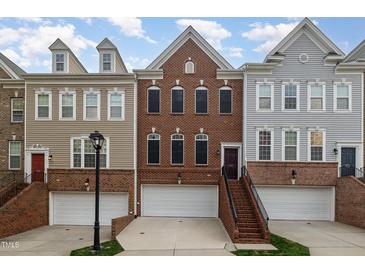 Exterior showcases brick townhomes featuring attached garages, landscaped entrances, and eye-catching architectural details at 4020 Abbey Park Way, Raleigh, NC 27612