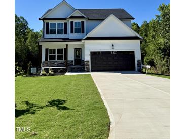 Charming two-story home featuring a well-manicured lawn, a two car garage, and stone accents at 60 Moonraker Dr, Spring Hope, NC 27882