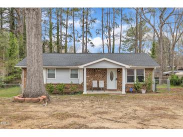 Charming single-story home featuring brick and vinyl siding, a covered porch, and mature trees in the front yard at 715 Shay Dr, Durham, NC 27704