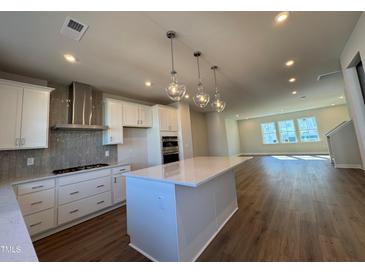 New kitchen features stainless hood, tiled backsplash, and eat-in island with pendant lights above at 802 Hillfarm Dr, Wake Forest, NC 27587