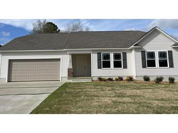 Charming single-story home with a manicured lawn, attached garage, and neutral color scheme at 103 Oakfield Trace Dr, Four Oaks, NC 27524