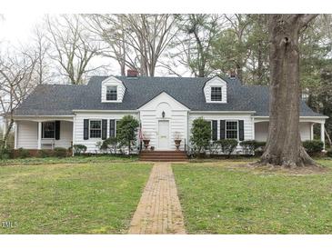 Charming two-story home with dormer windows, black shutters, brick walkway and mature landscaping at 105 John St, Louisburg, NC 27549