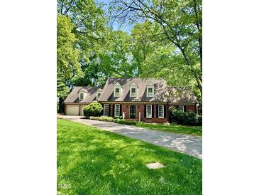 Charming brick home featuring a lush green lawn and mature trees at 3005 Woodgreen Dr, Raleigh, NC 27607