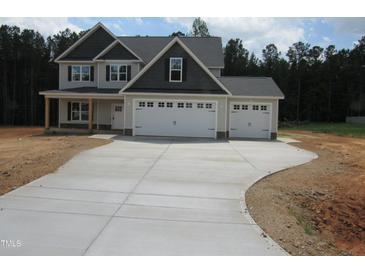Charming two-story home featuring a wide driveway and a three-car garage, set against a backdrop of lush trees at 358 Coats Ridge Dr, Benson, NC 27504