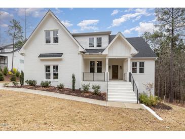 Stunning two-story white brick home with a welcoming front porch and manicured landscaping at 100 High Ridge Ln, Pittsboro, NC 27312