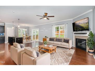 Bright living room featuring a fireplace, hardwood floors, ceiling fan, and an open floor plan with access to the kitchen at 101 Lager Ln, Garner, NC 27529