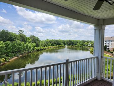 Scenic balcony view of a serene lake with a fountain, surrounded by lush greenery and a clear, blue sky at 10411 Rosegate Ct # 304, Raleigh, NC 27617