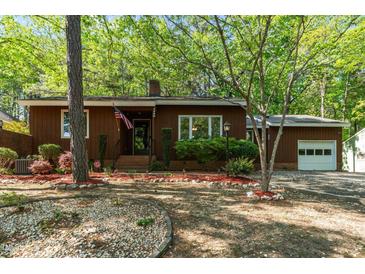 Charming single-story home featuring a well-manicured front yard with mature trees and garden beds at 1801 Irish Blvd, Sanford, NC 27332