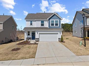 Charming two-story home featuring a two-car garage, landscaped yard, and a welcoming blue front door at 25 Carlton Ln, Franklinton, NC 27525