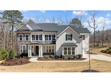 Beautiful two-story home with stone and white shingle siding, black shutters, and a well-manicured lawn at 7100 Hasentree Club Dr, Wake Forest, NC 27587