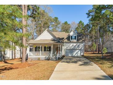 Charming home featuring a welcoming front porch, green shrubbery, and an attached two car garage at 138 Sherwood Ln, Sanford, NC 27332