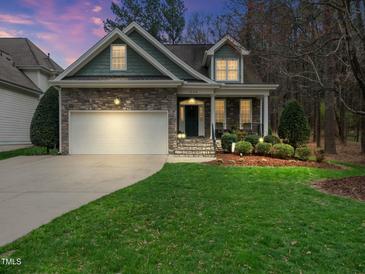 Charming home with stone accents, manicured lawn and inviting curb appeal at twilight at 1428 Heritage Links Dr, Wake Forest, NC 27587
