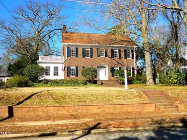 Traditional brick home featuring a red tile roof, green shutters, and a manicured front lawn at 1703 St. Mary'S St, Raleigh, NC 27608