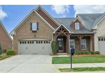 Charming brick home featuring a well-manicured lawn, covered porch with decorative columns, and an attached two-car garage at 1914 Tweed Ln, Burlington, NC 27215