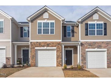 Townhome with tan siding, brick accents, a one-car garage, and a covered front entryway at 2834 Egert Dr, Haw River, NC 27258