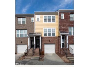 Charming townhome showcasing a brick facade, covered entrance, and attached garage, perfect for modern living at 317 Michigan Ave, Cary, NC 27519