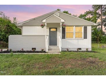 Charming single-story home with a well-manicured front yard and gray front door at 820 Newcombe Rd, Raleigh, NC 27610
