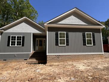 New construction home featuring gray siding, brick foundation, black shutters, and a covered front entryway at 977 Lewis Rd, Zebulon, NC 27597