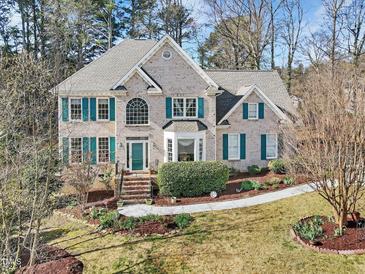 Charming two-story brick home with green shutters, manicured lawn and mature landscaping at 102 Stagville Ct, Cary, NC 27519