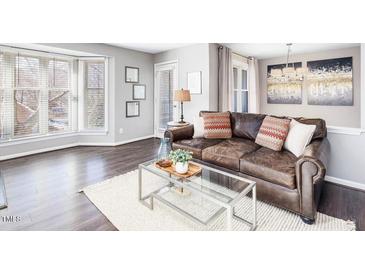 Cozy living room featuring a comfortable leather sofa, natural light from a bay window, and modern decor at 1051 Wirewood Dr # 202, Raleigh, NC 27605