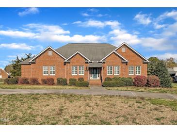 Classic brick home with white windows, complemented by manicured shrubs and a lush lawn, offering great curb appeal at 1220 Bethlehem Rd, Knightdale, NC 27545
