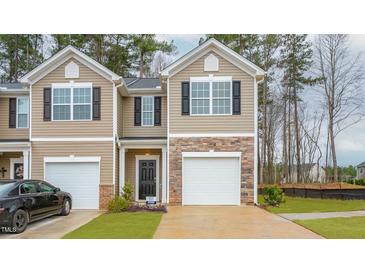 Charming townhouse features a stone accent, a single-car garage and neutral-colored siding at 1802 Brim Dr, Haw River, NC 27258