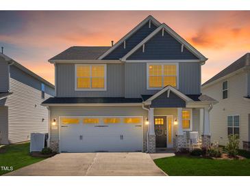 Charming two-story home featuring a two-car garage, and a welcoming front porch with a rocking chair at sunset at 2177 Campbell, Burlington, NC 27215