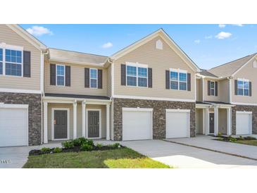 Two-story townhome exterior with stone accents, a garage, and a well-manicured lawn under a bright blue sky at 2838 Egert Dr, Haw River, NC 27258