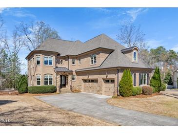 Stately brick home featuring a three-car garage and well-manicured landscaping at 3 Alumwood Pl, Durham, NC 27705
