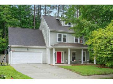 Charming two-story home featuring a red front door, covered porch, attached garage and landscaped yard at 4070 Landover Ln, Raleigh, NC 27616