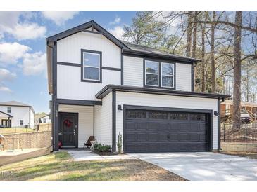 Two story home with black framed windows, a two-car garage, and a grassy front yard at 609 Rawls Dr, Raleigh, NC 27610
