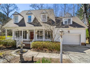 Charming home with a welcoming front porch, beautiful landscaping, and an attached garage at 102 Battenburg Ct, Cary, NC 27519