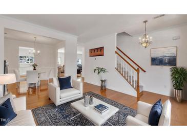 Bright living room with hardwood floors, white furniture, and a view of the dining area at 10707 Edmundson Ave, Raleigh, NC 27614