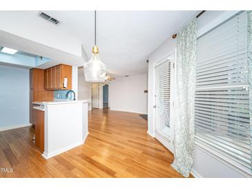 Bright open-concept living space with hardwood floors and a view into the modern kitchen at 109 Killam Ct # La, Cary, NC 27513