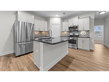 Modern kitchen features stainless steel appliances, center island, and stylish backsplash at 1103 Apogee Dr, Durham, NC 27713