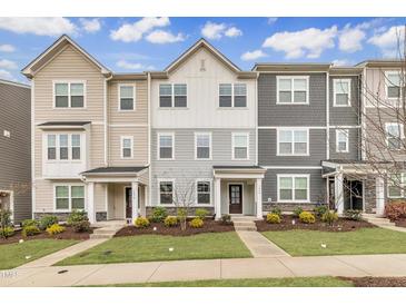 Charming townhome exteriors featuring varied siding and manicured lawns set against a bright, partly cloudy sky at 1434 Rosepine Dr, Cary, NC 27519