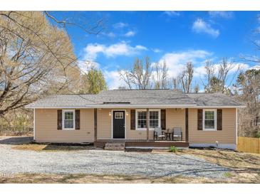 Charming home features tan siding, shutters, a covered front porch and well maintained landscaping at 2914 Old Stage N Rd, Coats, NC 27521