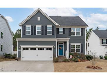 Charming two-story home featuring gray siding, black shutters, and a bright blue front door at 3727 Horton Hill Dr, New Hill, NC 27562