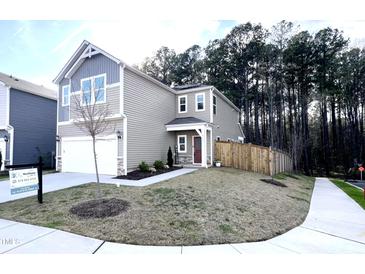Two-story home boasts neutral siding, attached garage, manicured lawn, and inviting curb appeal at 4000 Passenger Pl, Durham, NC 27703