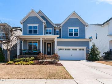 Charming two-story home with blue siding, a well-manicured lawn, and an attached two-car garage at 521 Ivy Arbor Way, Holly Springs, NC 27540