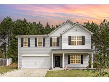 Charming two-story home features a two-car garage and classic black shutters set against a backdrop of lush, mature trees at 709 Conifer Ct, Creedmoor, NC 27522