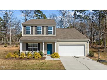 Charming two-story home featuring a well-maintained lawn, two-car garage, and inviting blue front door at 80 Westbrook Ln, Franklinton, NC 27525