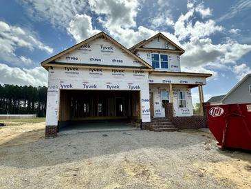 New construction home featuring a two-car garage and brick-accented entry, under construction, with a blue sky backdrop at 163 Noramac Ct, Selma, NC 27576