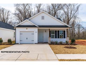 Charming single-Gathering home with a one-car garage, light blue door and a well-manicured lawn in front at 346 Bluejay St, Clayton, NC 27520