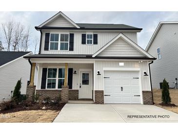 Charming two-story home showcasing a well-manicured lawn and a welcoming entrance, with a white garage door at 354 Bluejay St, Clayton, NC 27520