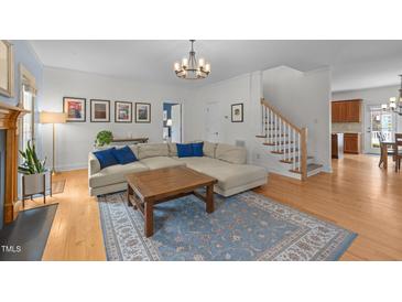 Bright living room features hardwood floors, a decorative rug, a sectional sofa, and a modern light fixture at 445 S Greensboro St, Carrboro, NC 27510