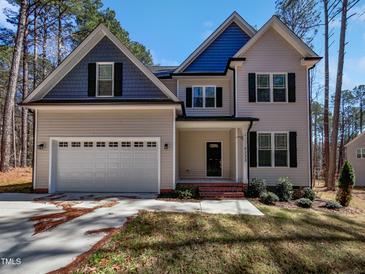 Charming two-story home featuring a manicured lawn, attached two-car garage, and eye-catching blue and tan color scheme at 6233 Reagan Ln, Wake Forest, NC 27587