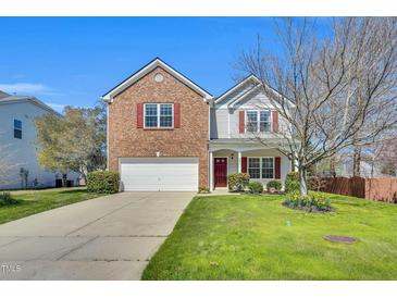 Charming two-story home featuring a brick facade, red shutters, a well-maintained lawn, and a two car garage at 6817 Osprey Landing Dr, Wendell, NC 27591